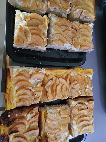 2 assiettes sombres recouvertes de parts carrées de gâteau dont on devine l'appareil clair sous les tranches de pommes.