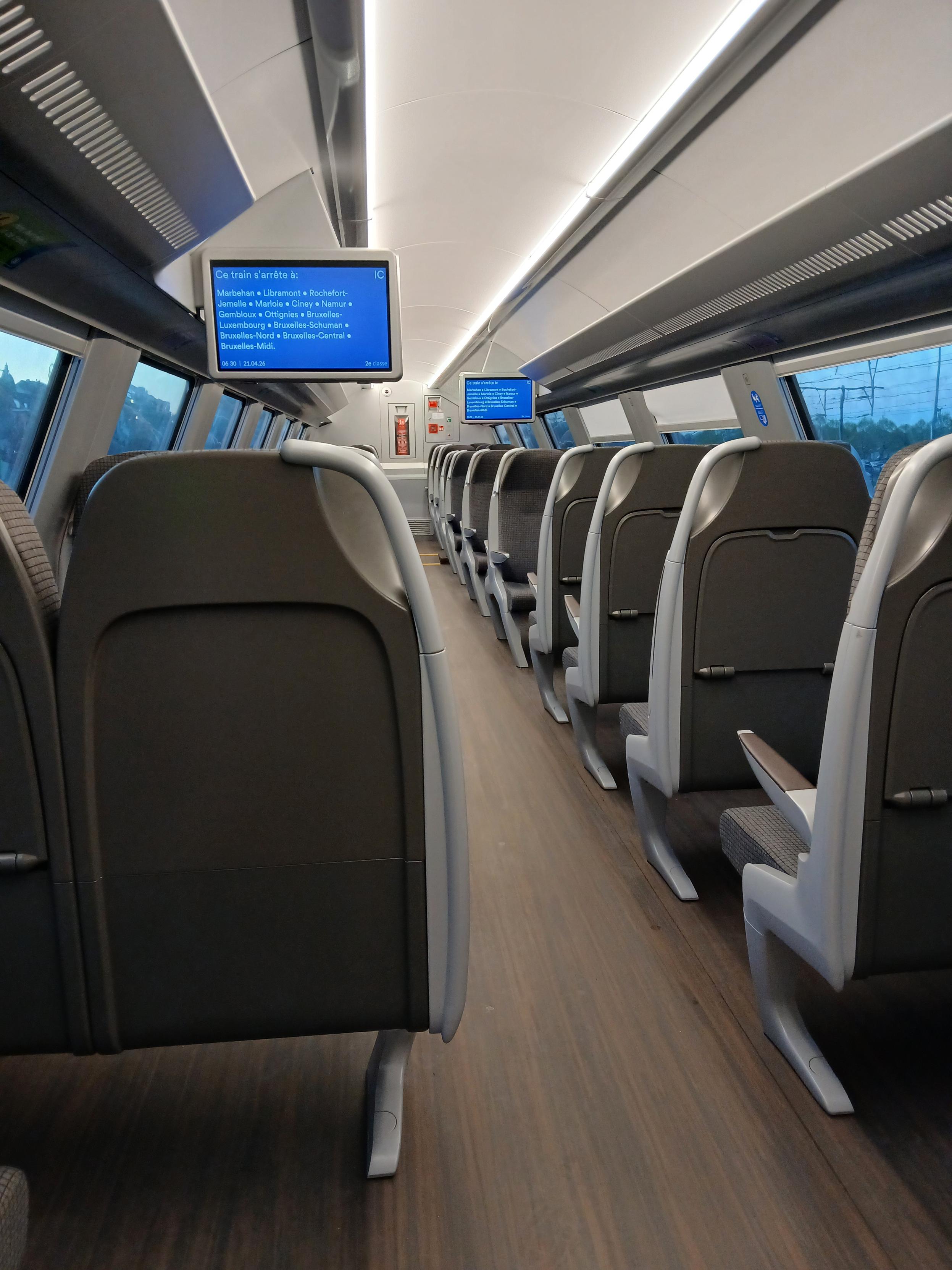 Intérieur d’un train à l’étage supérieur d’une voiture à deux étages. Les écrans affichent tous les arrêts du train. 

Interior of a train at the upper level of a bi-level carriage. The screens are qhowing all the stops.