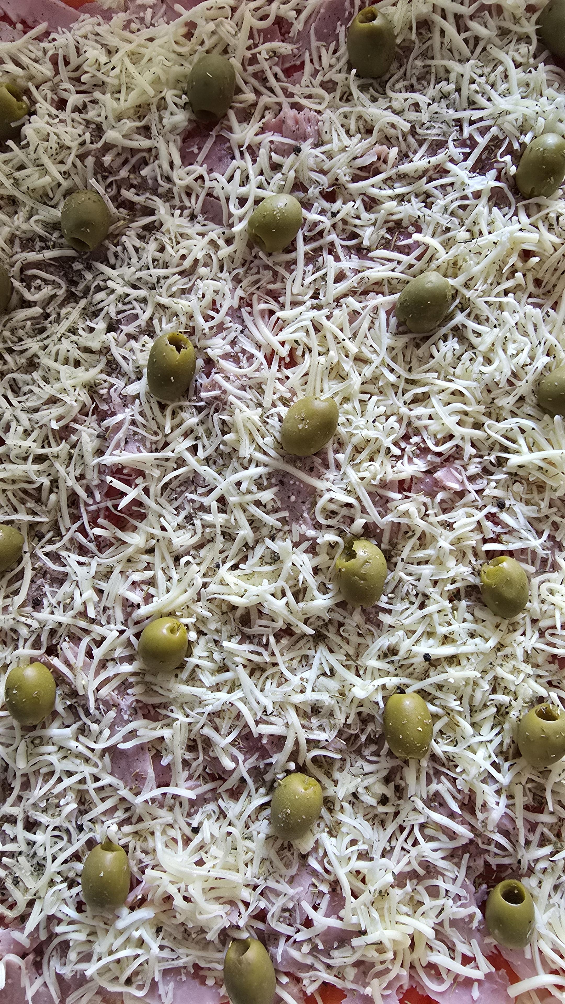 Pizza maison à enfourner : pâte maison, tomates bio, jambon blanc, emmental et olives vertes.