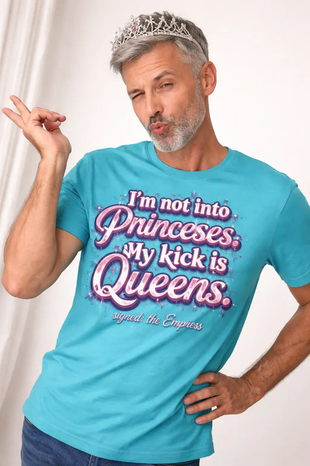 Fit sexy silver haired daddy who's wearing a tiara, and a turquoise tee-shirt with the text: "I'm not into princesses. My kick is Queens. Signed: the Empress". His pose is very camp with a duck pout and a wink.