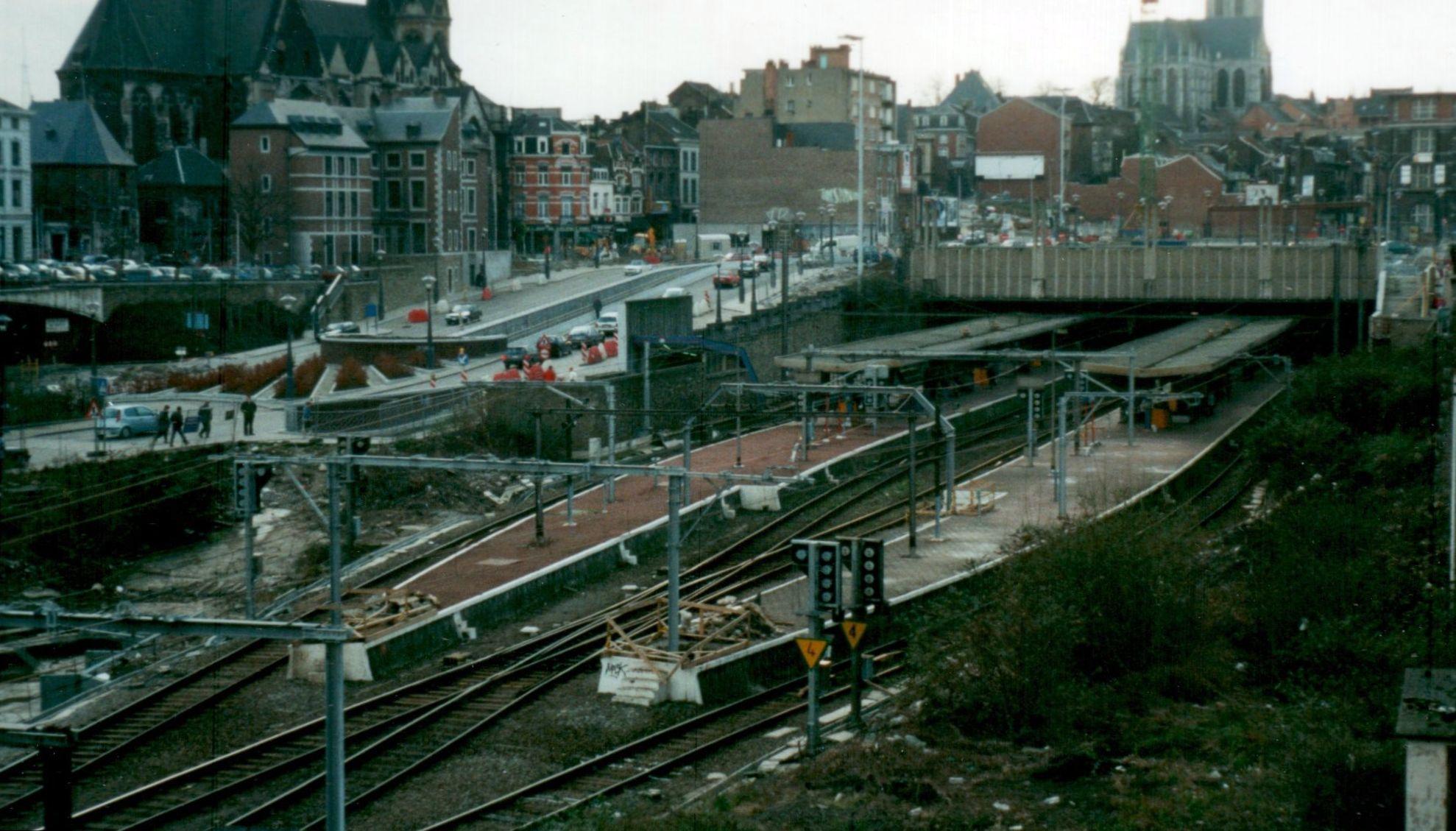 Une gare ferroviaire à deux quais et quatre voies. Les voies pénètrent sous une dalle qui fait office de tunnel. L'environnement est urbain et deux églises sont visibles en partie sur la photo (à gauche et à droite dans le haut de la photo). 

A railway station with two platforms and four tracks. The tracks enter under a slab which acts as a tunnel. The environment is urban and two churches are partly visible in the photo (left and right at the top of the photo).