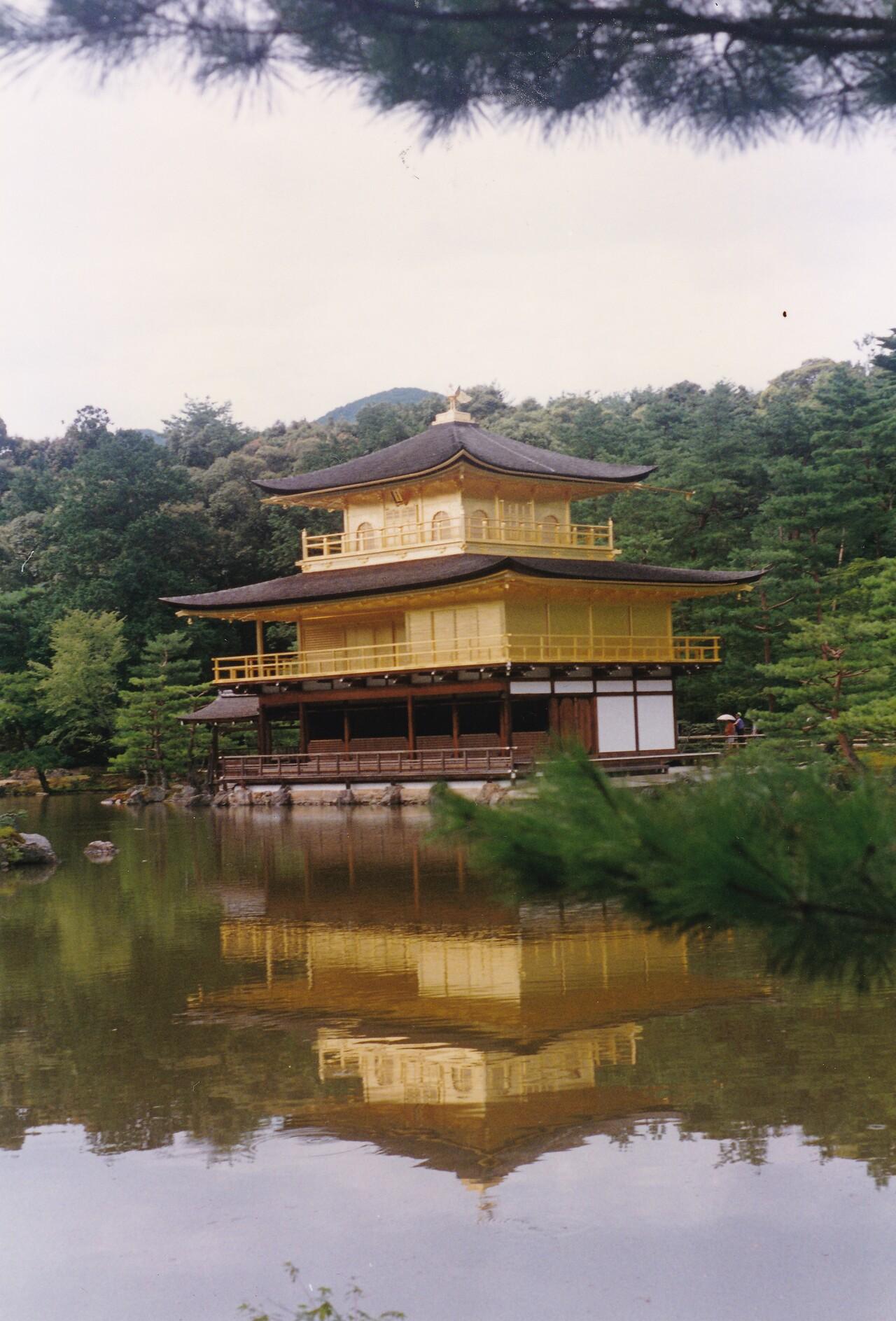 Le Pavillon d’Or ou Kinkakuji à Kyoto au Japon, temple traditionnel en bois recouvert d’or, entouré d’arbres et se reflétant dans un étang.