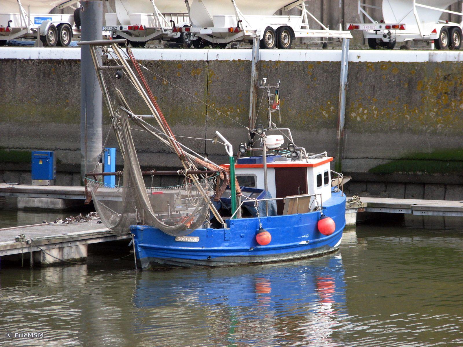 Un petit chalutier bleu ciel avec bouées oranges dans le port d'Oostende.

A small sky blue trawler with orange buoys in the port of Oostende.
