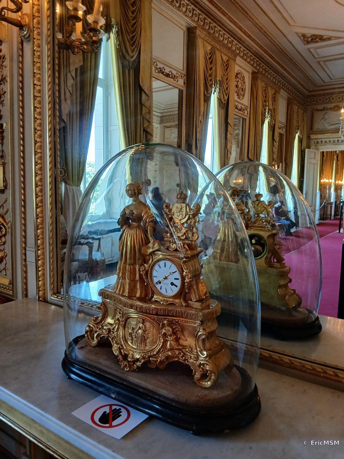 Une belle horloge avec une petite statuette  posée sur une cheminée.

A beautiful clock with a small statuette placed on a fireplace.