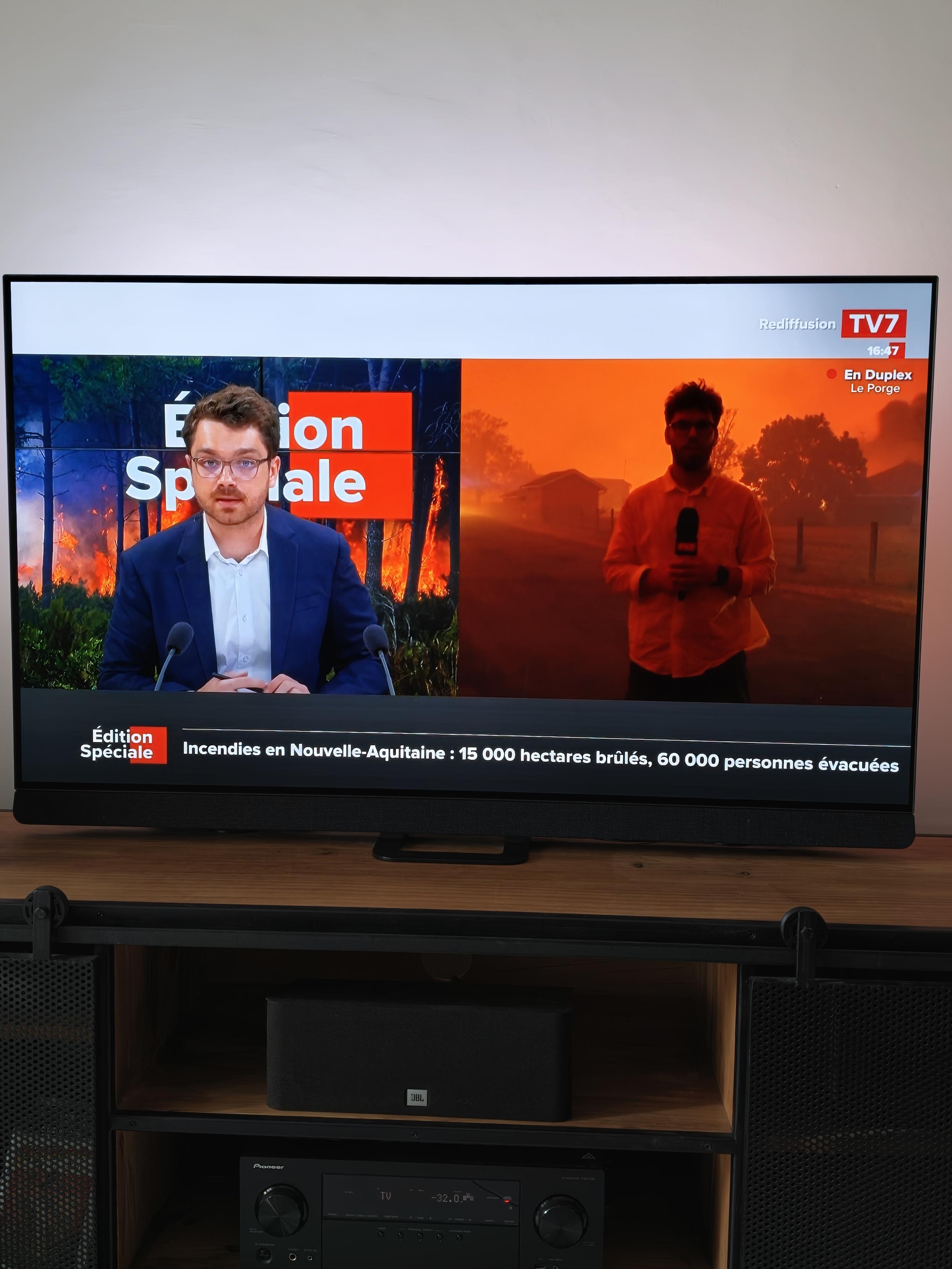 Photo de la Tv avec un direct sur l'incendie : le journaliste est dans une lumière orange et noire