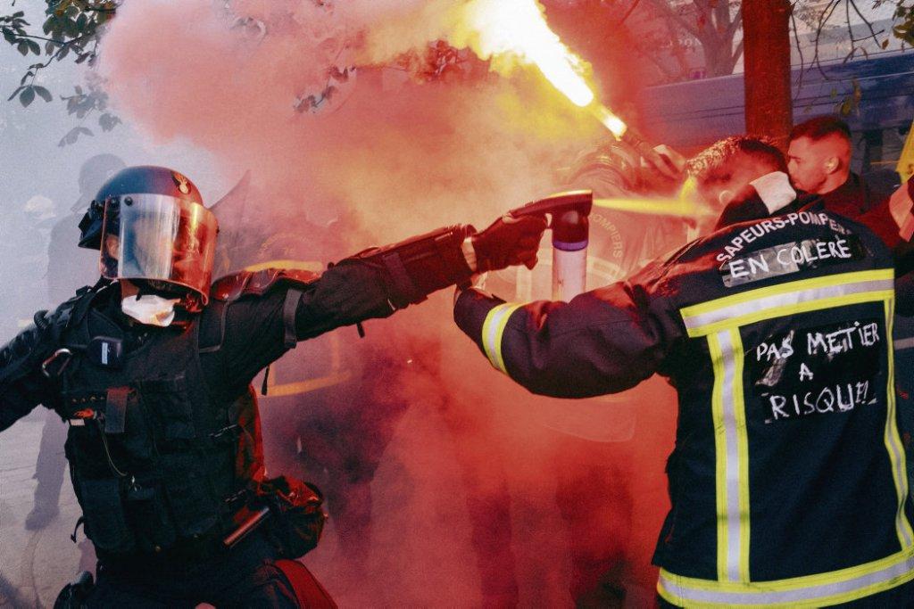 Un pompier se faisant gazer à bout portant par un policier lors de manifestations pour réclamer de meilleurs moyens
