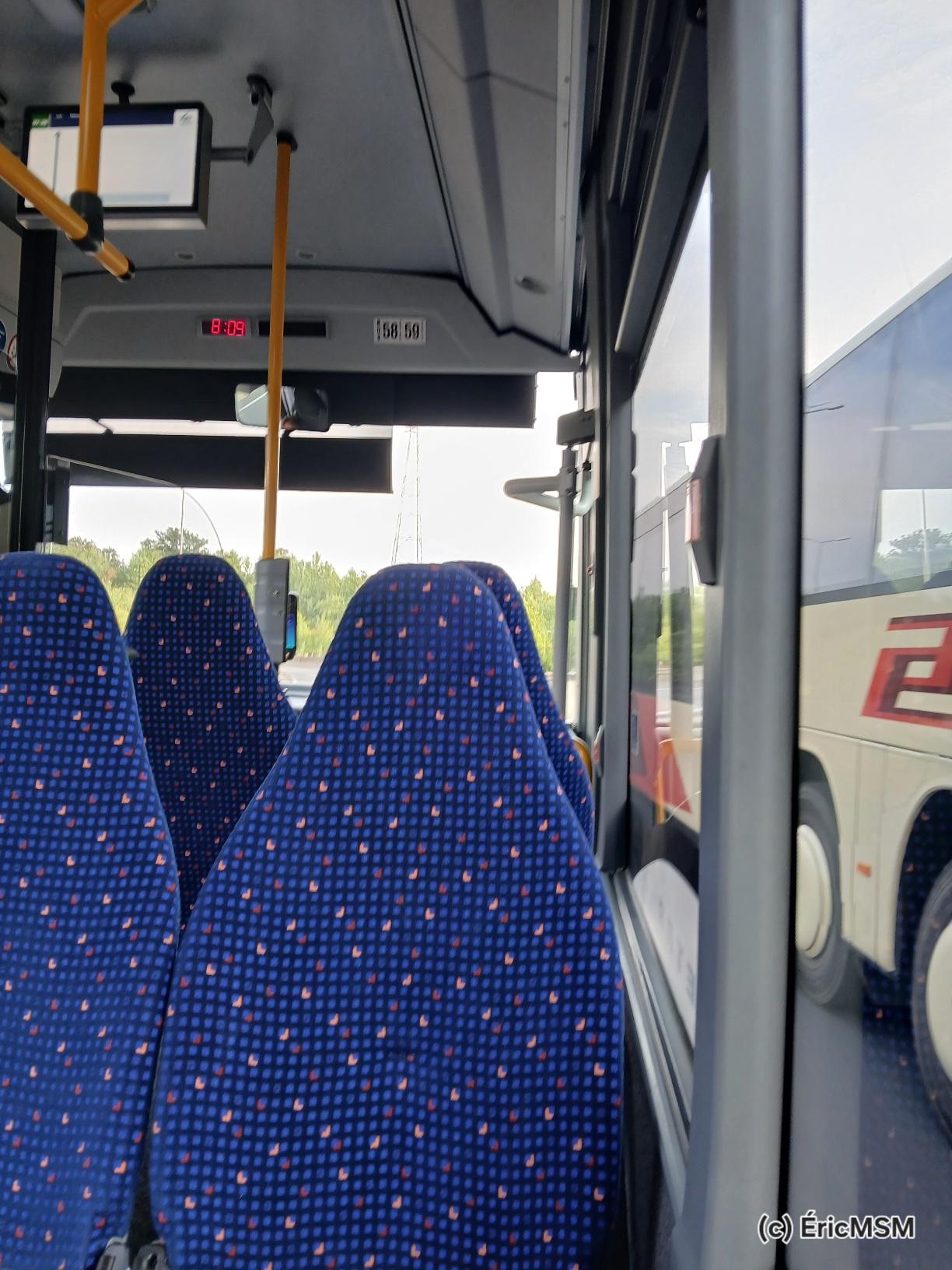Intérieur d’un bus. Sièges bleus tachetés en velours.