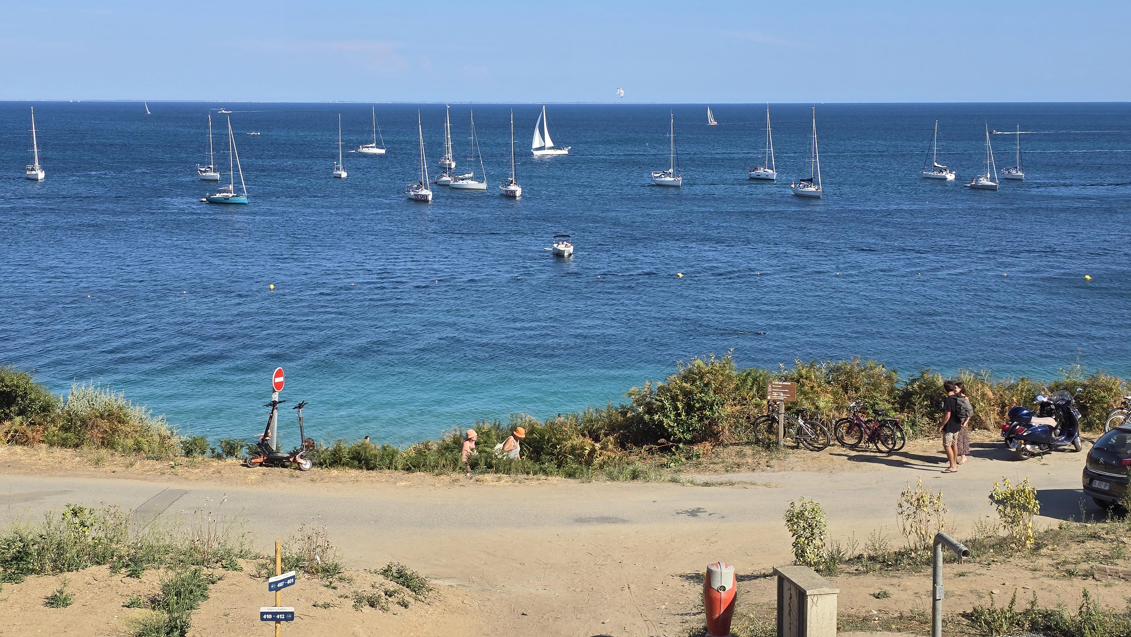 La plage des grands sables sur l'île de Groix en Bretagne, avec la mer bleue et les voiliers à l'horizon.
