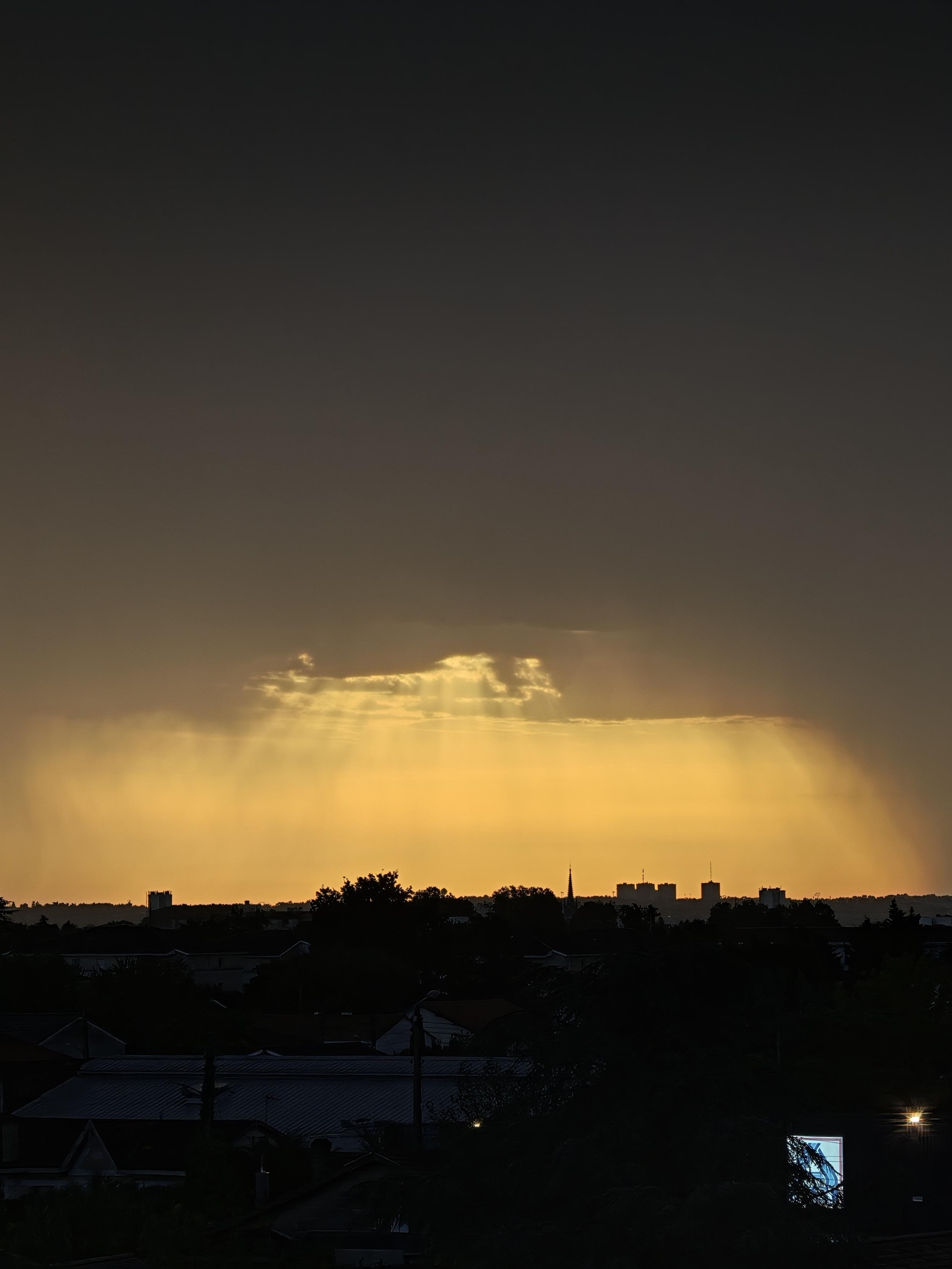 Ciel noir avec une zone orangée et des rayons lumineux tombants du ciel.
